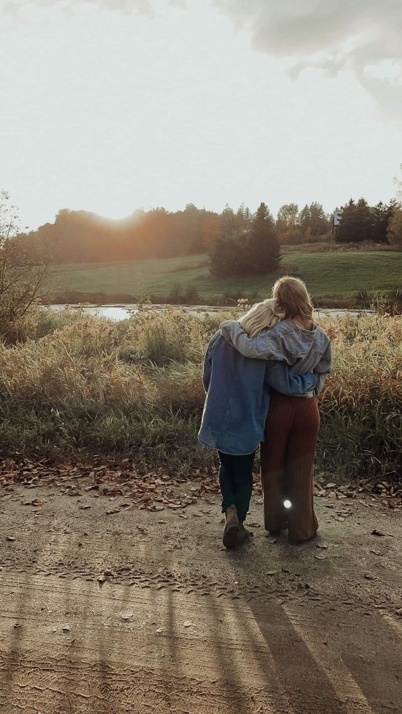 Couple enlacé contemplant la nature près d’un étang au coucher du soleil
