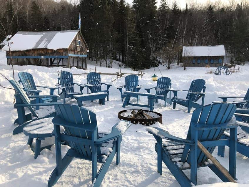 Chaises Adirondack bleues autour d’un foyer extérieur en hiver