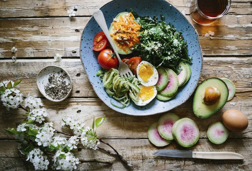 Assiette santé avec légumes, avocat et œufs sur une table en bois