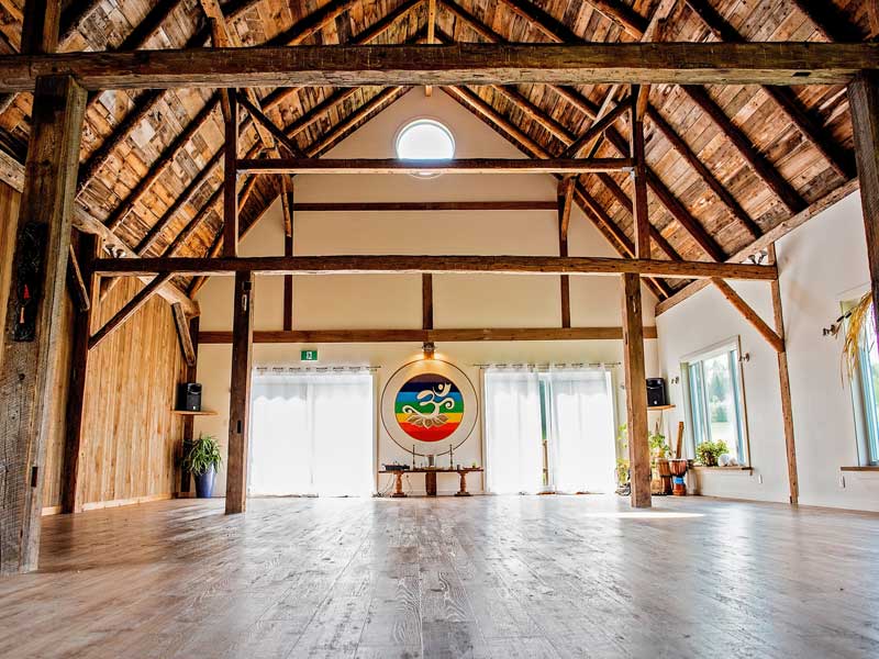Salle de yoga aux poutres de bois et grandes fenêtres