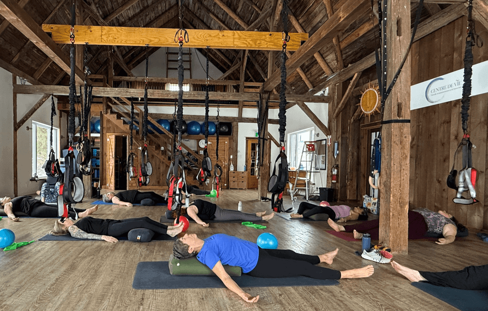 Cours de pilates au sol dans la salle aux poutres de bois
