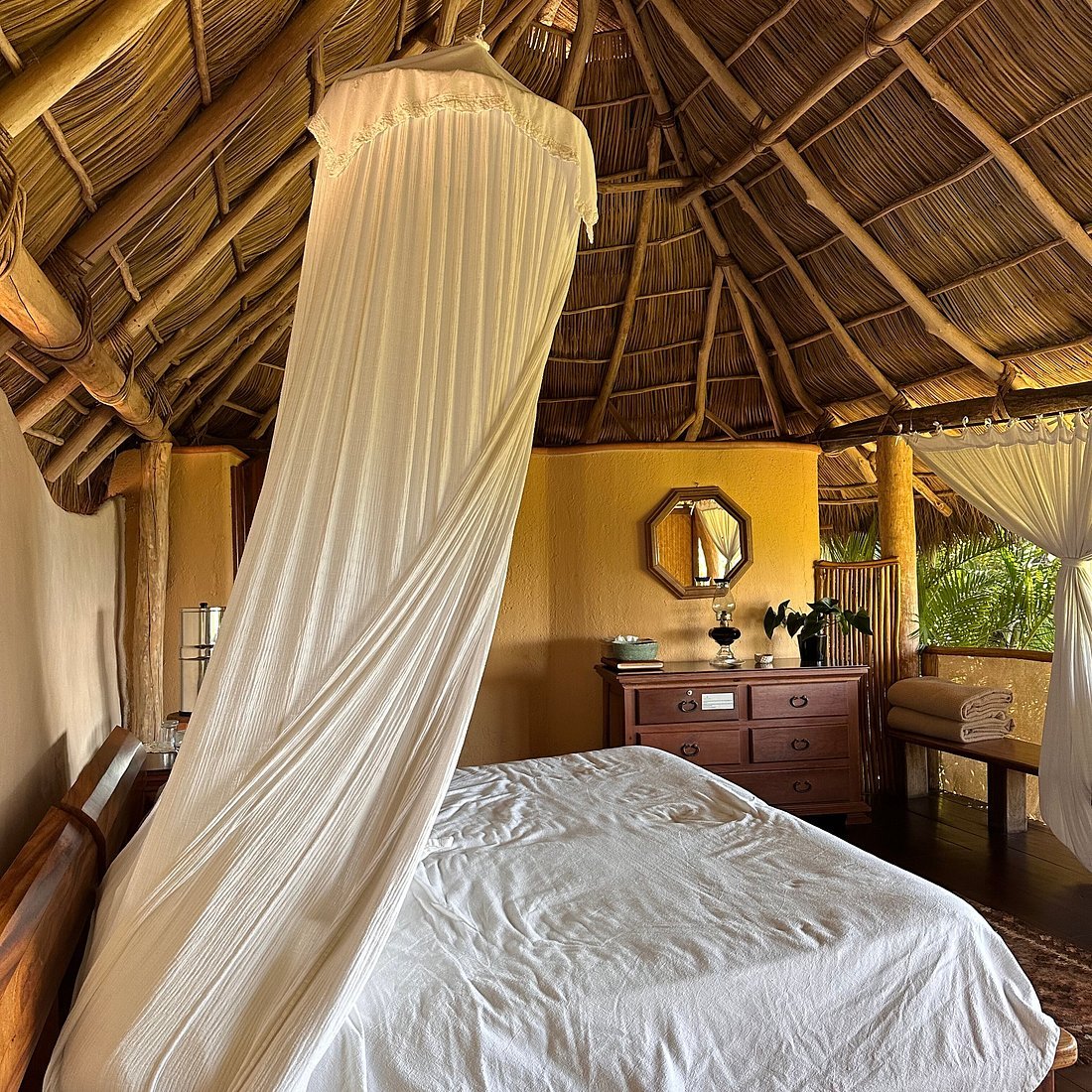 Chambre d’une casita au Haramara Retreat, lit à baldaquin sous toit de palmes